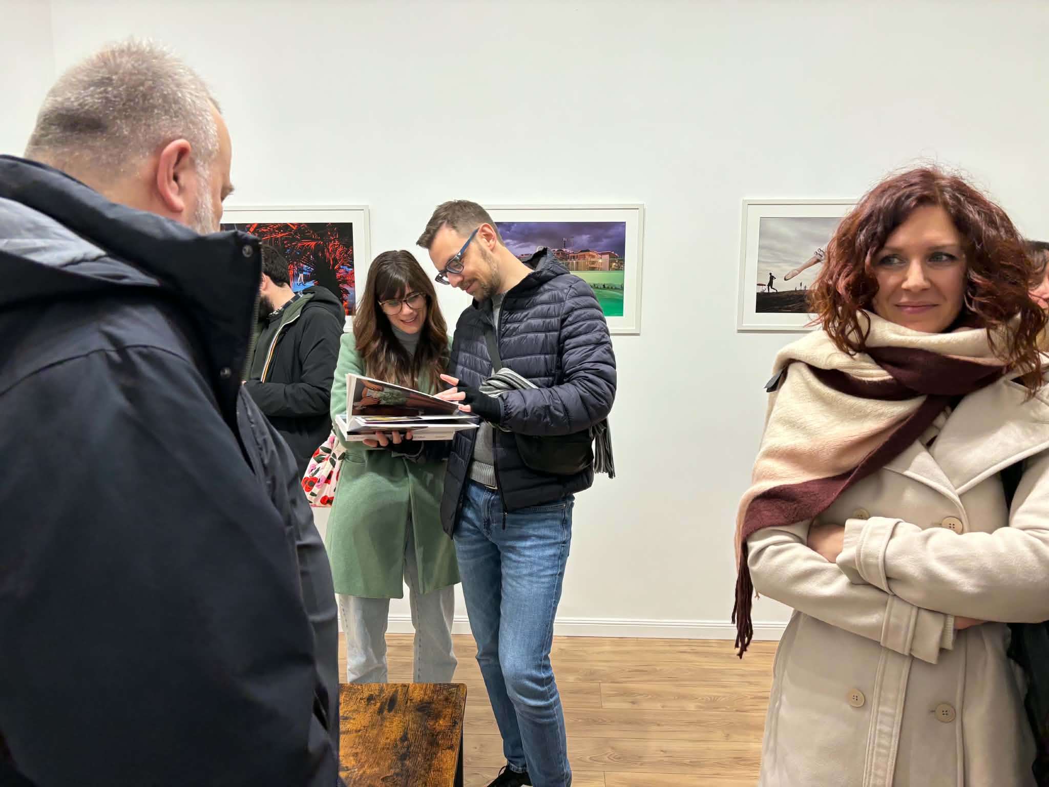 Visitors flip through the book *Mareterno* among the works of the Daylight School
